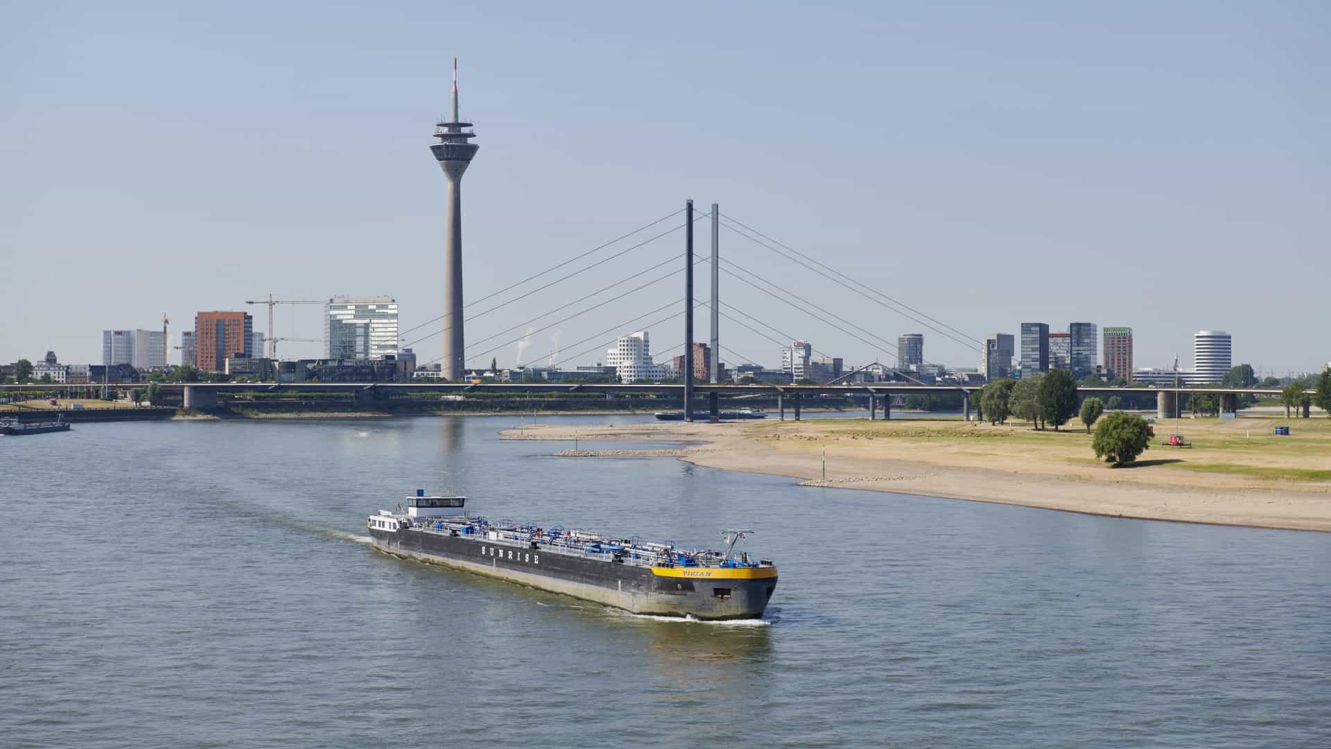 Aufnahme vom Rhein in Düsseldorf. Ein Tanker fährt auf dem Rhein und im Hintergrund steht der Fernsehturm.